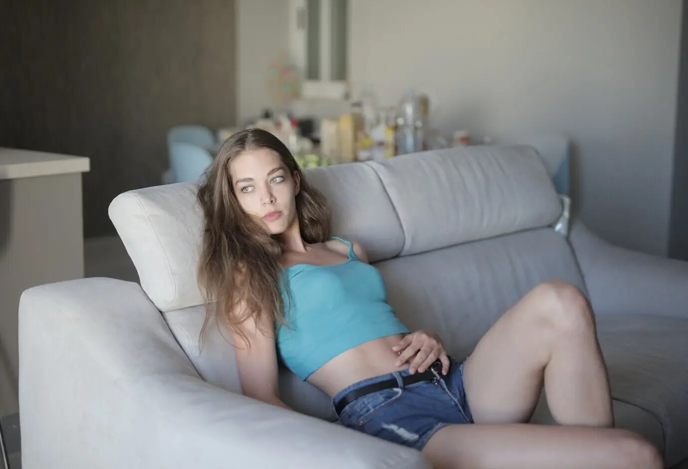 A young, beautiful woman is sitting on the sofa and resting.