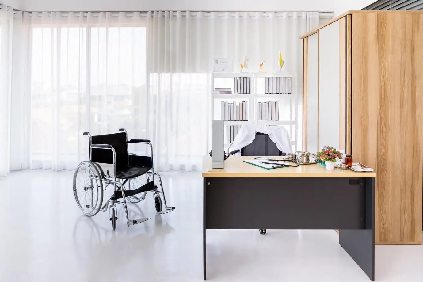 Interior of an empty medical doctor's office in a hospital clinic with a wheelchair.